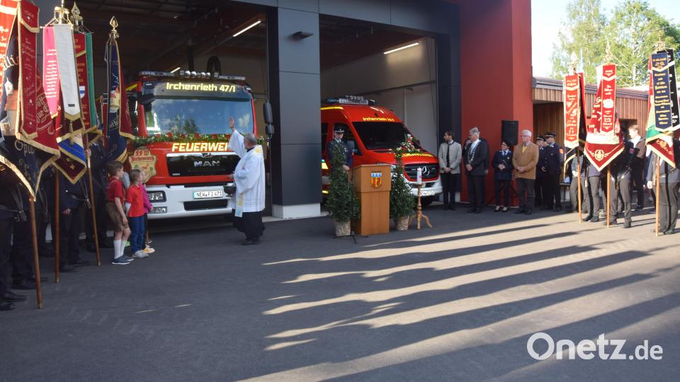 Pfarrer Alfons Forster segnet das neue Feuerwehrhaus und die beiden Einsatzfahrzeuge. Die Vereine mit ihren Fahnen bilden ein Spalier. Bild: fz