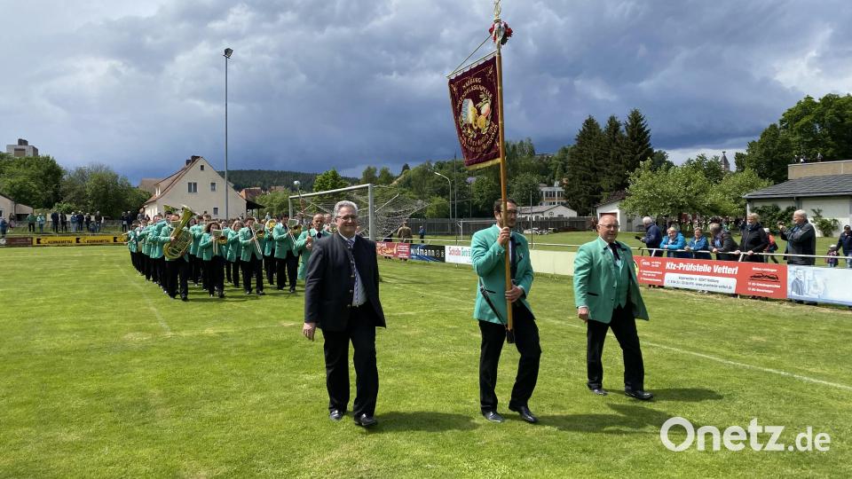 Die Gastgeber mit Standarte, Schirmherr Pfarrer Hannes Lorenz und Vorstand Josef Ferstl marschierten voran auf den Sportplatz, wo sie schon von zahlreichen Zuschauern erwartet wurden. Bild: aub