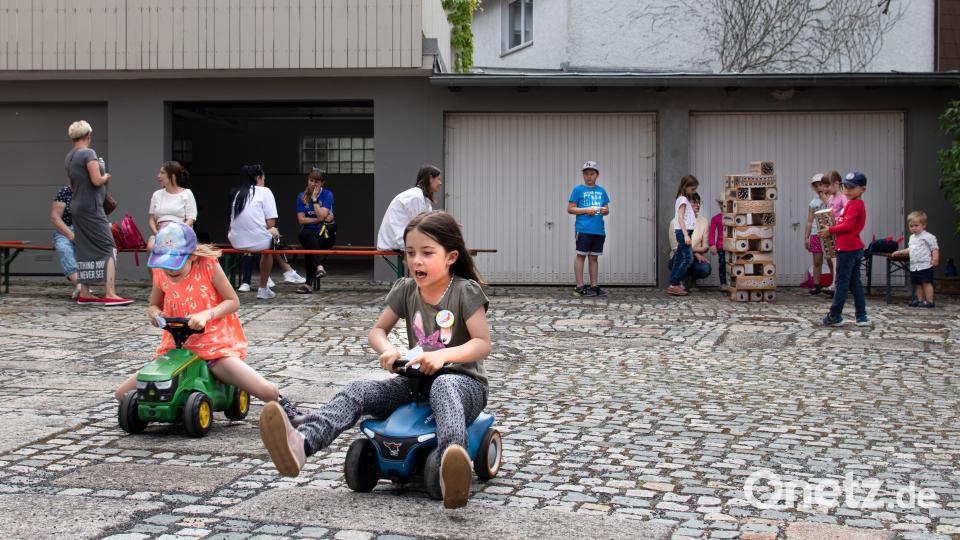 Beim Spielenachmittag am Gelände beim Pfarrgarten in Bärnau trafen sich ukrainische und deutsche Kinder. Zwei Mädchen fahren mit Bobby-Cars um die Wette, während andere Kinder mit dem Riesenwackelturm spielen. Mütter haben auf Bierbänken Platz genommen. Bild: sfo