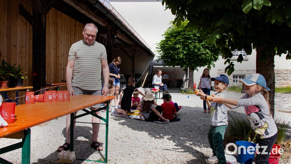 Die Kinder haben Spaß beim Spielen mit Wasserspritzpistolen. Auch Kolpingfamilie-Vorsitzender Markus Fichtner schaute bei dem Spielenachmittag vorbei. Im Hintergrund spielt Theresa Schmid (stehend, links) von der BRK-Bereitschaft Bänau mit den Kindern &quot;Doktor Bibber in groß&quot;. Bild: sfo