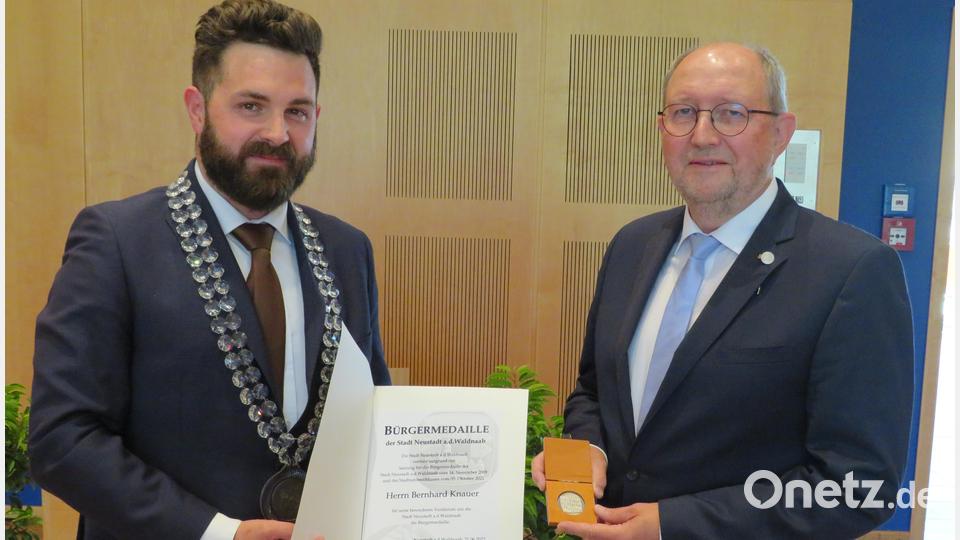 Bürgermeister Sebastian Dippold (links) überreicht die Ernennungsurkunde und Medaille an Bernhard Knauer (rechts). Bild: adj