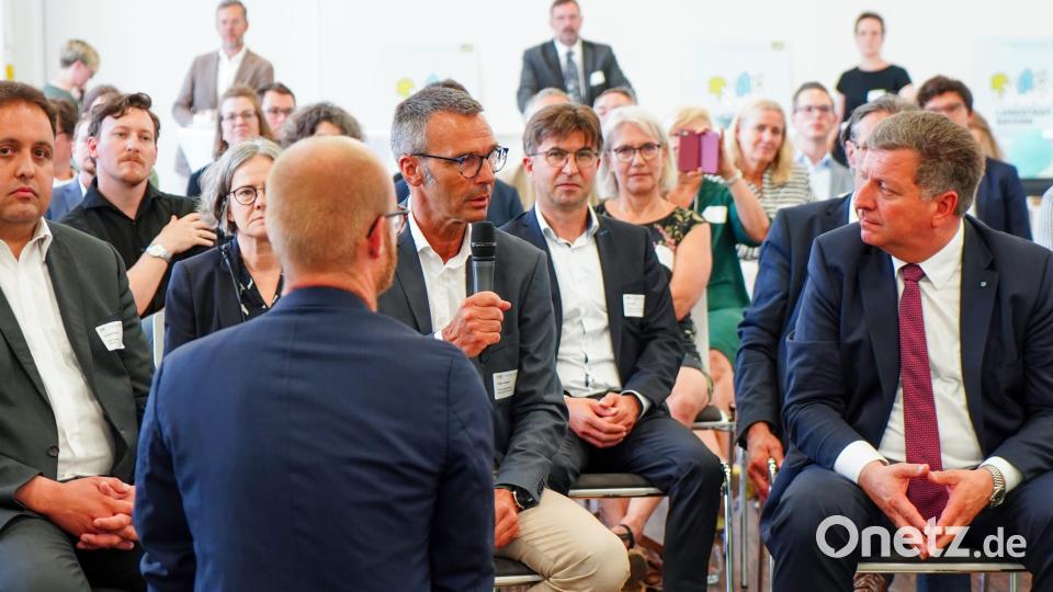 Für zwei Minuten hält Neukirchens Bürgermeister Peter Achatzi das Mikrofon in der Hand: Mehr Zeit bekommt er nicht, um Bauminister Christian Bernreiter (rechts) das Schulhaus-Projekt in Neukirchen vorzustellen. Bild: StMB_Winszczyk/exb