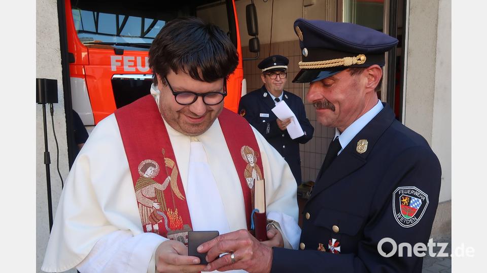 Der Kaplan von St. Josef, Pater Johannes Bosco (links), bekommt von Stadtbrandrat Richard Schieder die St.-Florians-Medaille der Feuerwehr Weiden. Im Hintergrund Vorsitzender Peter Stahl. . Bild: Kunz