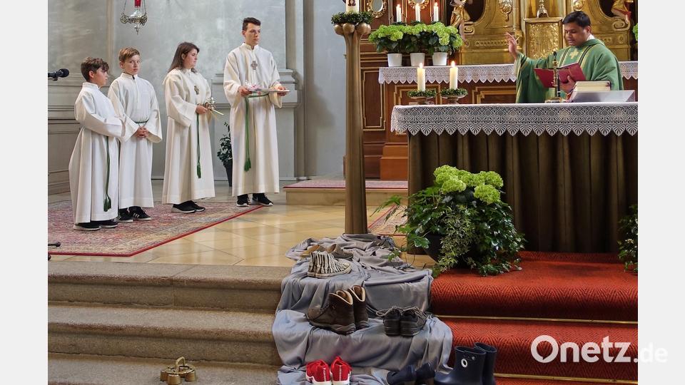 Korbinian Blei und David Monath zusammen mit Katharina Schnurrer und Maximilian April bei der feierlichen Aufnahme durch Pater Martin (Reihenfolge von links). Im Vordergrund die verschiedenen Schuhe auf dem Weg, der zur Osterkerze führt. Bild: exb/Michaela Staufer
