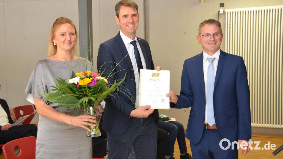 Mittelschulrektor Hubert Reil (rechts) überreichte Konrektor Michael Neumann (Mitte) die Ernennungsurkunde zum Konrektor. Lebenspartnerin Caro Kaufmann (links) erhielt einen Blumenstrauß. Bild: dob