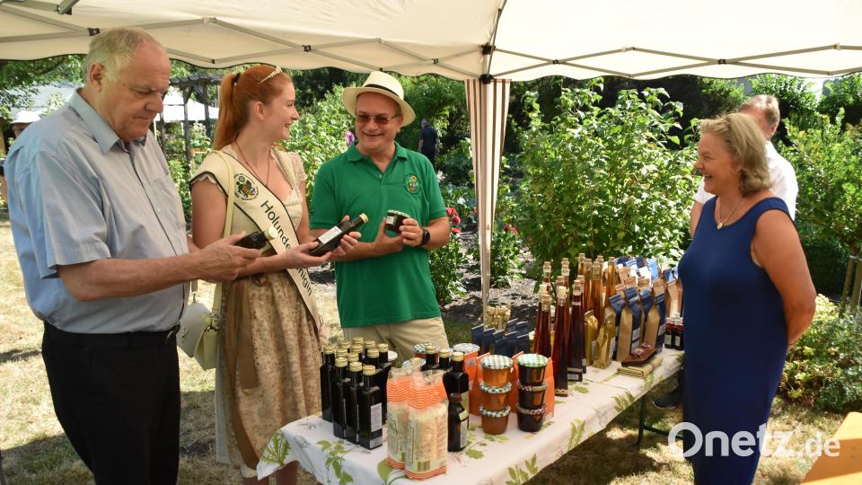Bürgermeister Lothar Höher, Holunderkönigin Monika Bernhard und Obst- und Gartenbauvereins-Vorsitzender Klaus Fischer begutachten die Naturprodukte - darunter Holundersirup - von Kräuterfachfrau Gisela Klier. Bild: hcz