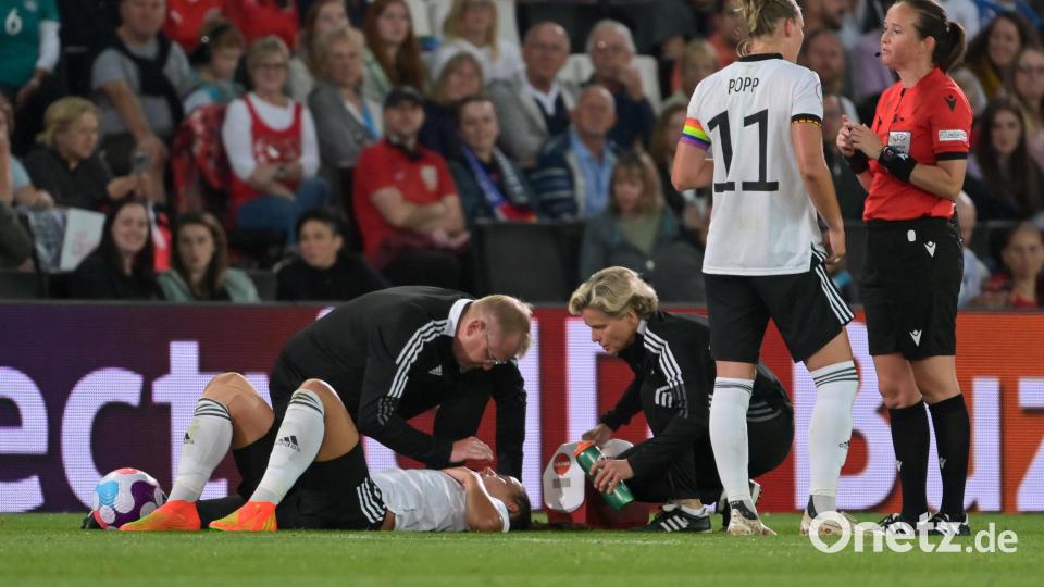Lena Sophie Oberdorf liegt am Boden und wird behandelt. Alexandra Popp bespricht sich währenddessen mit Schiedsrichterin Cheryl Foster. Bild: Sebastian Gollnow