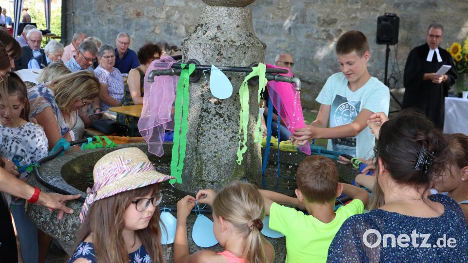 Die Kinder und Jugendlichen schmückten im Verlauf des Gottesdienstes den wieder zum Laufen gebrachten Brunnen im Kirchhof. Bild: flt