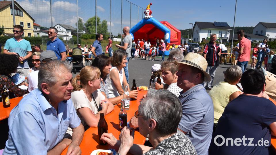 Beim Spielplatzfest treffen sich die Erwachsenen und die Kinder toben im Hintergrund in der Hüpfburg Bild: fz