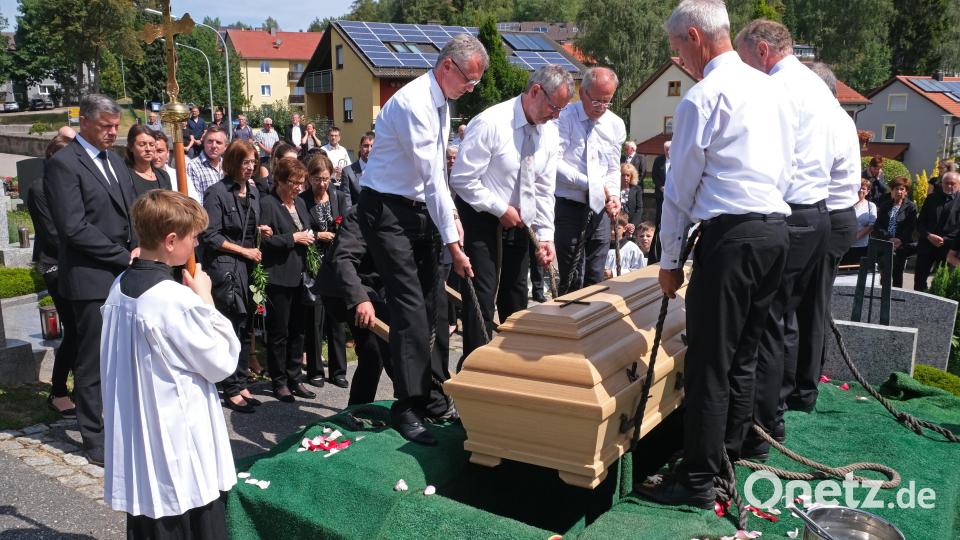 Sechs Sangesfreunde lassen den Sarg mit John Werner in das Grab hinab. Zahlreiche Trauernde nehmen Anteil am letzten Weg des Altbürgermeisters. Bild: nm