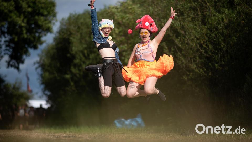Vivien und Maria springen auf dem Campingplatz des Wacken Open Air Festivals in die Luft. Das WOA gilt als größtes Heavy-Metal-Festival der Welt. Bild: Daniel Reinhardt/dpa