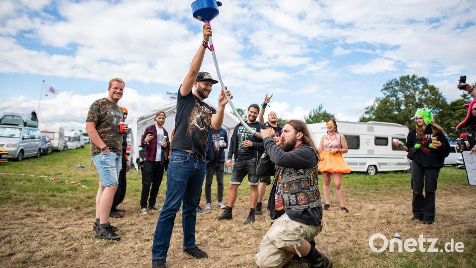 Ein Mann trinkt auf dem Campingplatz des Wacken Open Air Festivals Bier aus einem Schlauch. Das WOA gilt als größtes Heavy-Metal-Festival der Welt. Bild: Daniel Reinhardt/dpa