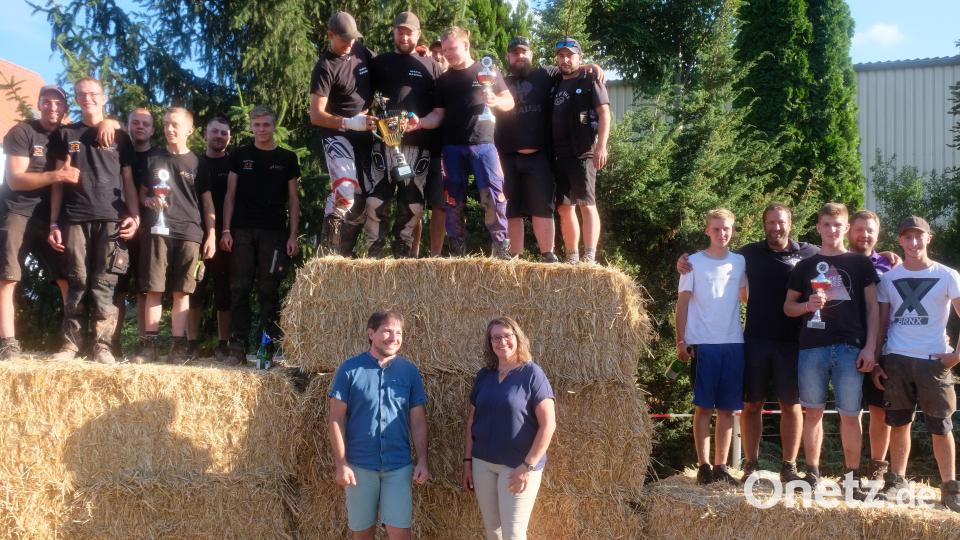 Auf Strohballen jubeln die drei erstplatzierten Teams des 24 Stunden-Mofa-Rennens gemeinsam mit ihrem Begleitpersonal. Rennleiter Stefan Groß und Bürgermeisterin Carmen Pepiuk freuen sich mit Bild: do
