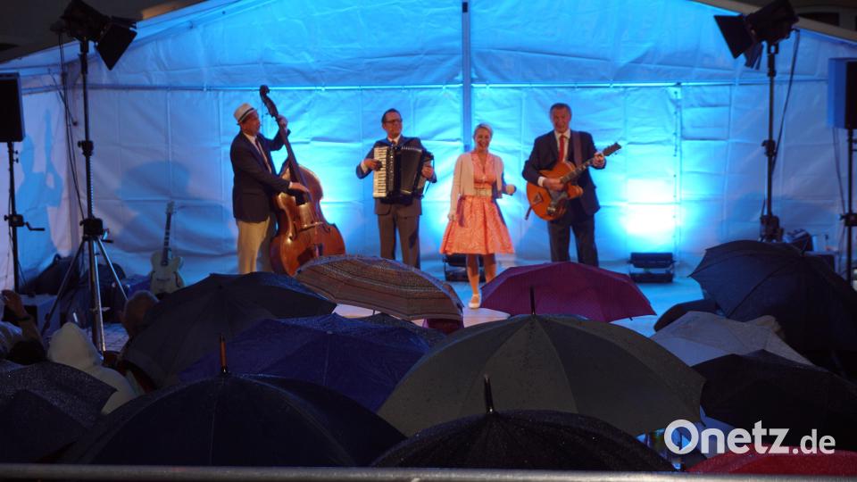 Die Gäste vor der Band unter Regenschirmen Bild: bkr