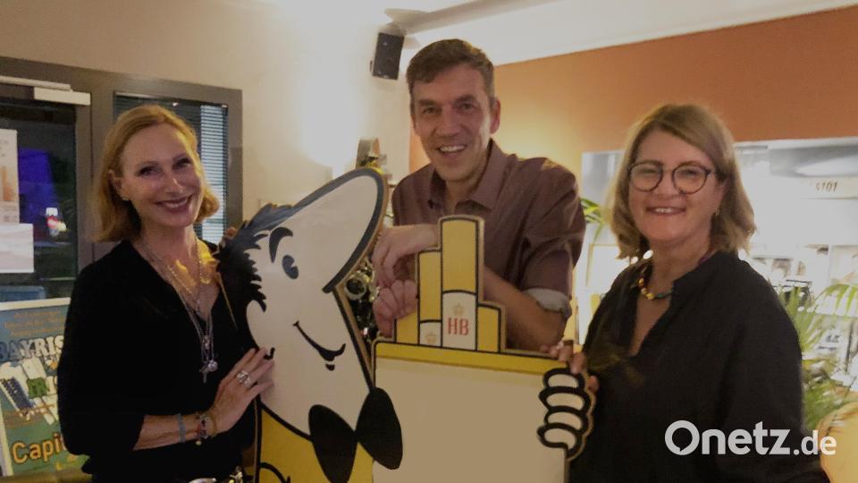 Nach der Lesung entdeckte Andrea Sawatzki (links) im Beisein von Buchhändler Ralf Volkert und dessen Mitarbeiterin Marion Romeis im Capitol das Deko-HB-Männchen aus der Kino-Werbung. In ihrem neuen Buch &quot;Brunnenstraße&quot; spielt die Werbefigur auch eine kleine Rolle. Bild: Thilo Hierstetter