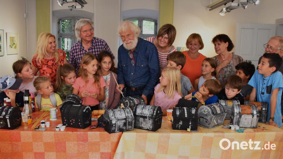 Künstler Siegfried Rahner (Mitte) aus Bärnau hat die Schatzkistchen vorbereitet und zeigte den Kindern zu Beginn des Bastelnachmittags, was zu tun ist. Gern schauten ihm auch seine Künstlerkollegen, die zur Betreuung der Buben und Mädchen gekommen waren, über die Schultern. Bild: ubb