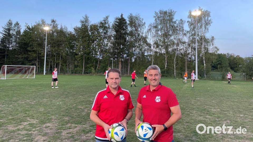 Sportlicher Leiter Marco Ringer und Vorsitzender Christian Koch (von links) freuen sich über die Verbesserungen auf dem Sportgelände, während im Hintergrund die Erste Mannschaft in den frühen Abendstunden unter dem neuen Flutlicht trainiert. Bild: lei