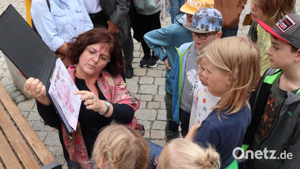 Stadtführerin Tanja Weiß zeigte den Kindern auf einem alten Stadtplan, wo das Feuerwerk stattfand, das den Stadtbrand ausgelöst hat. Bild: cog