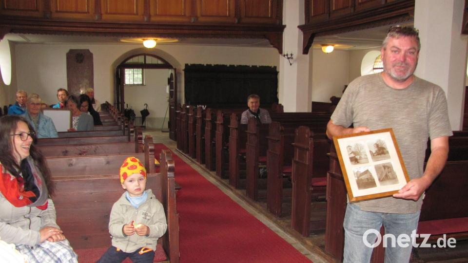 Harald Stengel, stellvertretender Vertrauensmann der evangelischen Kirchengemeinde, zeigt bei der Führung Fotos, wie die Kirche früher Innen und außen ausgesehen hat. Bild: sei