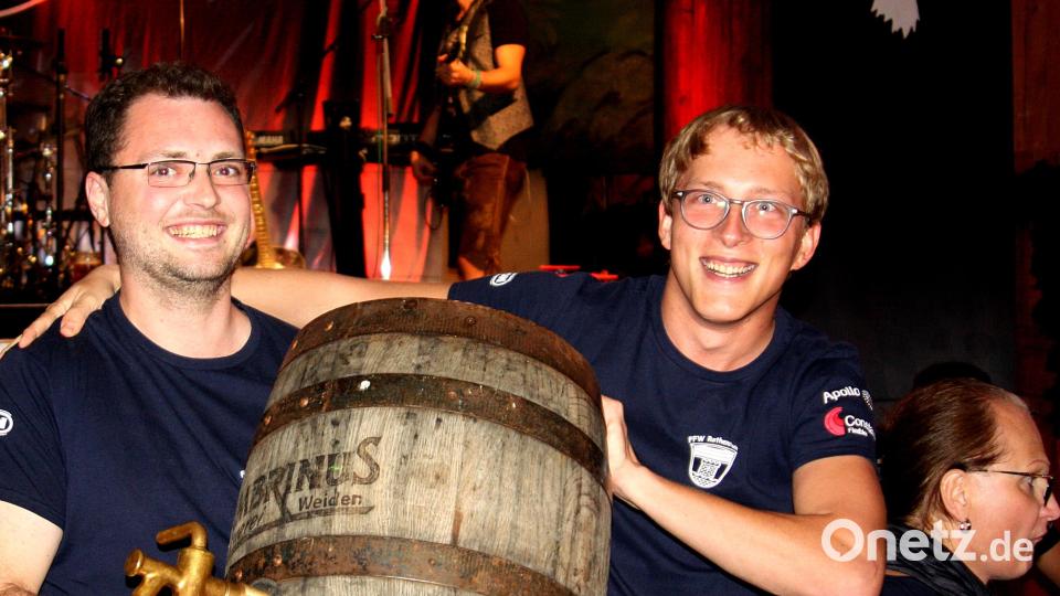 Kommandant Michael Hösl und Andreas Schramek von der Feuerwehr Rothenstadt haben das angebrochene Fass von der Bühne geholt, um es am Tisch mit den Kameraden zu leeren. Bild: R. Kreuzer