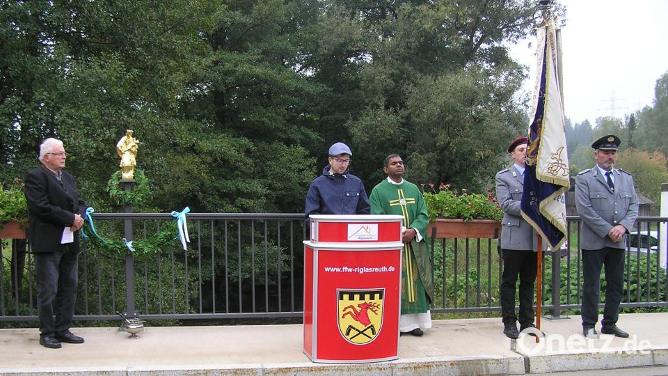 Vor der feierlichen Segnung informierte Max Pirner (am Rednerpult) über das Leben es heiligen Johannes Nepomuk. Richard Stock (von links), Pfarrer Julius Johnrose und die Abordnung der Soldaten- und Reservistenkameradschaft Riglasreuth hörten aufmerksam zu. Nicht mit im Bild die Fahnenabordnungen der Feuerwehr und Kolpingfamlie. Bild: öt