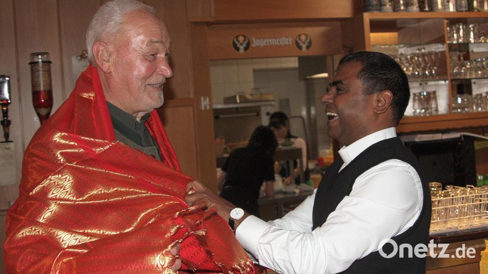 Auf humorvolle Art gratulierte Pfarrer Johnrose (rechts) den Geburtstagsjubilar Norbert Reger. Mitgebracht hatte der Geistliche in rotes Tuch, mit dem er Reger fest umwickelte. Bild: wro