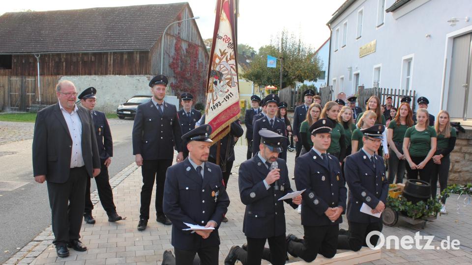 Kniend versuchen als Vertreter der Ransbacher Feuerwehr (von links) Zweiter Kommandant Manuel Ruscheinski, Zweiter Vorsitzender Dieter Borckert, Vorsitzender Christoph Finn und Kommandant Andreas Bruckmüller den Utzenhofer Feuerwehrleuten die Übernahme der Patenschaft schmackhaft zu machen. Zweiter Bürgermeister Manfred Braun und die Festdamen beobachten das Patenbitten. Bild: aun