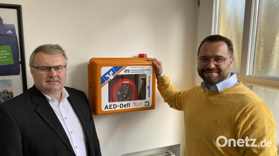 Geschäftsstellenleiter Wolfgang Meister (links) und Bürgermeister Matthias Grundler vor dem Defibrillator im Eingangsbereich der Bank in Falkenberg. Bild: Volksbank Raiffeisenbank/exb