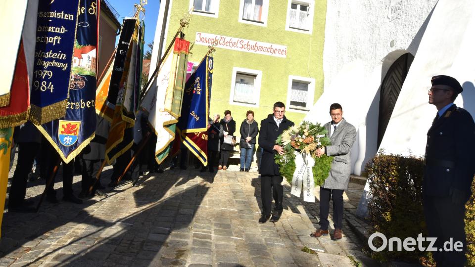 Der Vorsitzende der SRK Illschwang, Fritz Falk (links), und der Zweiter Bürgermeister Benjamin Hiltl legen, bei gesenkten Fahnen, einen Kranz am Kriegerdenkmal nieder. Eine Ehrenwache hatte dort Aufstellung genommen. Bild: no