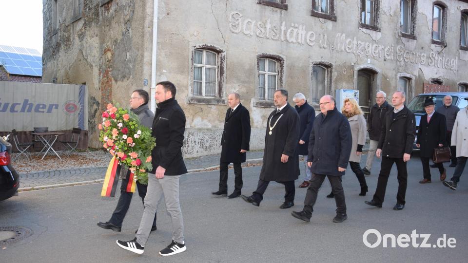 Bürgermeister Josef Beimler (mit Amtskette) , begleitet von den Markträten der Gemeinde, auf dem Weg zum Kriegerdenkmal. Die Markträte Michael Troidl (links) und Georg Stahl (rechts) tragen den Kranz, der später am Kriegerdenkmal abgelegt wird. Bild: fla