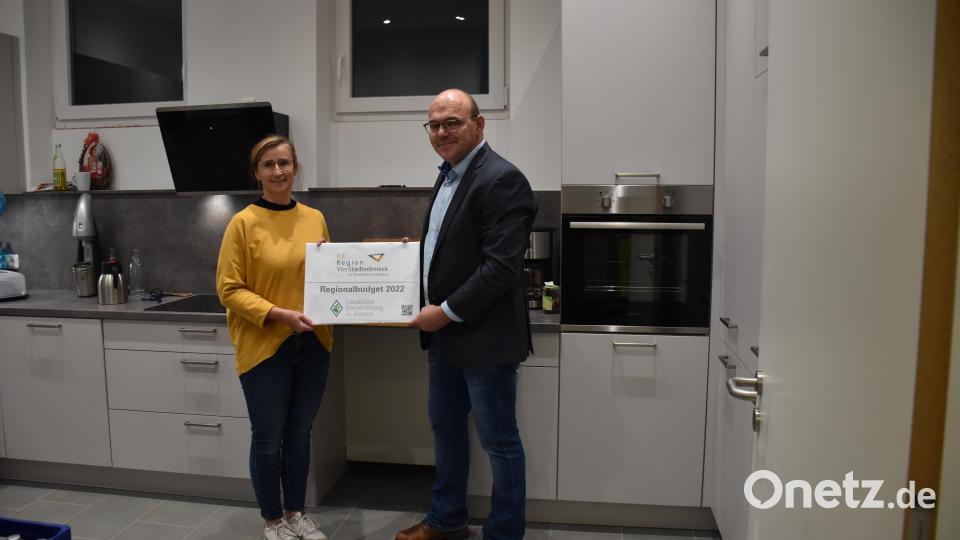 Erster Bürgermeister der Gemeinde Schlammersdorf Johannes Schmid und Gemeindemitarbeiterin Monika Schramm bei der Übergabe des Förderschilds in der neuen Gemeinschaftsküche im Bürgerhaus Schlammersdorf Bild: ILE/exb