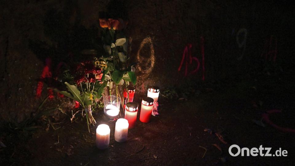 Blumen und Kerzen stehen an Markierungen der Spurensicherung der Polizei an einem Tatort auf einem Weg. Zwei Mädchen wurden auf ihrem Schulweg angegriffen und schwer verletzt. Bild: Bernd Weißbrod/dpa