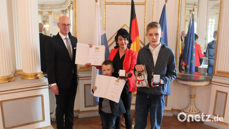 Regierungspräsident Walter Jonas zeigt das Foto nach den Ehrungen mit Lebensretterin Steffi Günther (mit Sohn Paul) und Lebensretter Franz-Josef Heigl (von links). Bild: Regierung der Oberpfalz/Schmied/exb