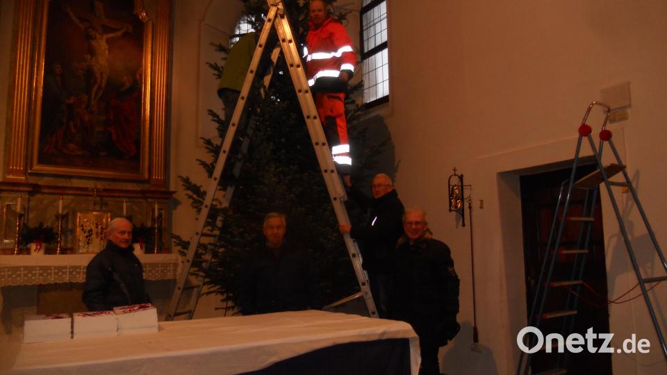 Alexander Klettner (auf der Leiter) ist der Dienstälteste der Feuerwehrtruppe, die seit Jahren den Baum in der katholischen Kirche in Flossenbürg schmückt. Bild: jba