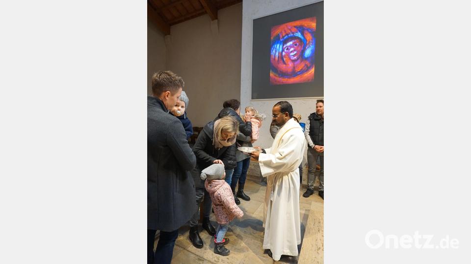Die Eltern segnen ihre Kinder mit Weihwasser in Erinnerung an deren Taufe . Mit Pfarrer Sagaiaraj Lourdusamy (rechts) Bild: wec