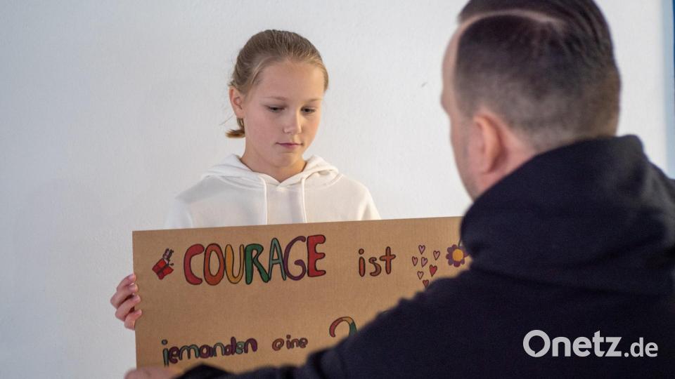 Eine der Schülerinnen hält ein Schild zum Thema Courage in die Kamera. Bild: Christian Kaminsky