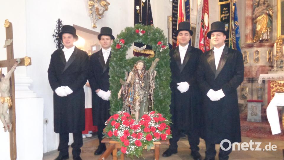 Vier junge Männer tragen die geschmückte Statue. Bild: amö