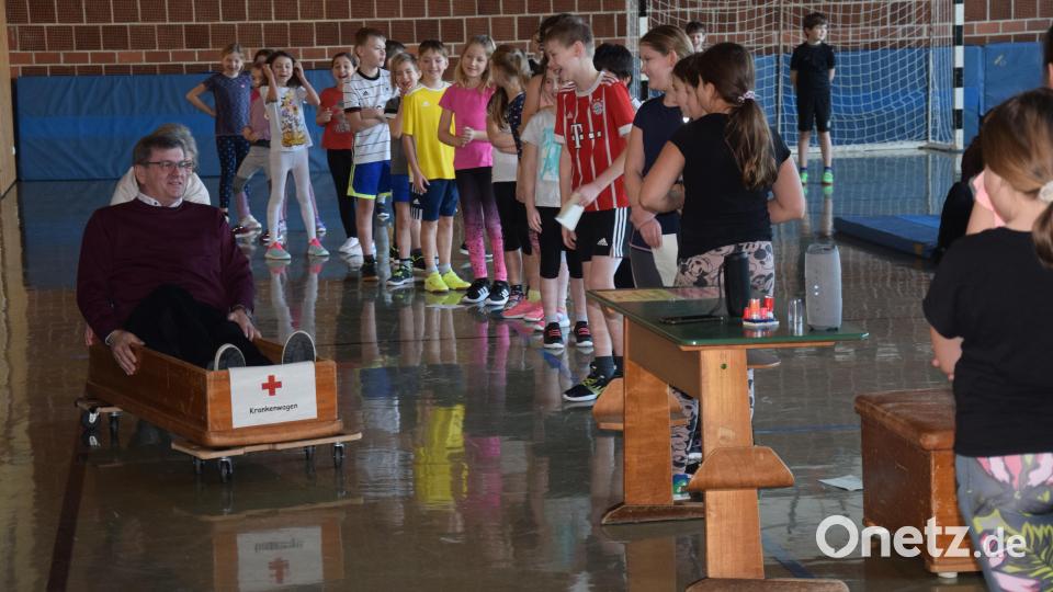 Gegen einen gutes Entgelt schiebt Rektorin Sabine Lubich in einem provisorischen Krankenwagen den Schmidmühlener Bürgermeister Peter Braun eine Runde durch die Turnhalle. Bild: bö