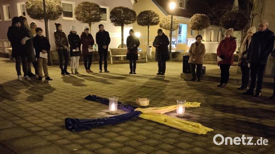 Mehr als 50 Personen beteiligen sich am Jahrestag des Kriegsbeginns am Friedensgebet auf dem Kirchplatz. Stadtpfarrerin Carmen Riebl und Claudia Reindl gestalten die Feier. Bild: dob