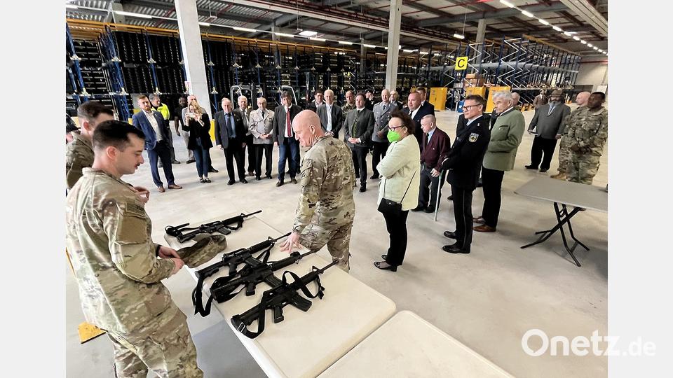 8000 Trainingshilfen und Gerätschaften werden in der großen Lagerhalle vorgehalten. Brigadegeneral Hilbert (Mitte) stellte den Gästen unter anderem Handfeuerwaffen-Dummys vor. Bild: mor