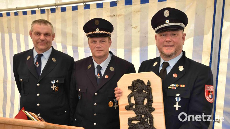 Zwei Vertreter der Nachbar-Feuerwehr Ursensollen überreichen an Jörg Flierl (links) ein Bildnis der Heiligen Florian. Bild: no