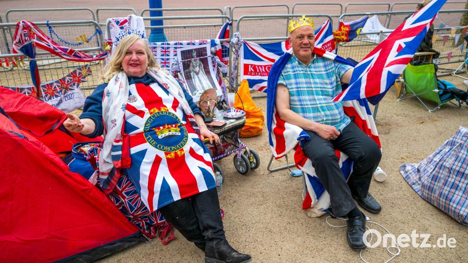 Royal-Fans sitzen an der Straße „The Mall“ vor dem Buckingham Palace. Bild: Sina Schuldt/dpa