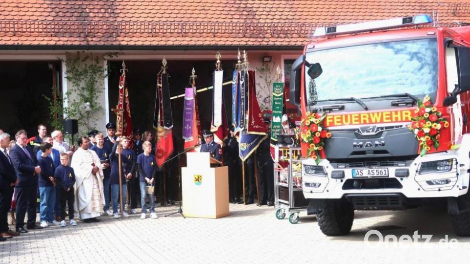 Doppelten Grund zum Feiern hat die Vilsecker Wehr am Florianstag. Stadtpfarrer Pater Robin Xavier segnet zwei neue Einsatzfahrzeuge. Kommandant Lothar Hasenstab (am Rednerpult) dankt Bürgermeister Hans-Martin Schertl (Dritter von links) für die Unterstützung. Bild: rha