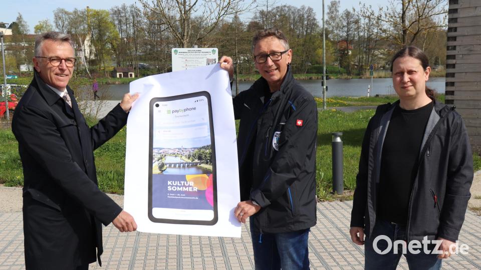 Bürgermeister Franz Stahl, Bauamt-Projektleiter Robert Reith und städtischer IT-Leiter Christian Pößl (von links) mit einem Plakat, dass die Startseite der neuen App „PayByPhone“ zeigt, die das Parken am Wohnmobilstellplatz erleichtert. Bild: Stadt Tirschenreuth/exb