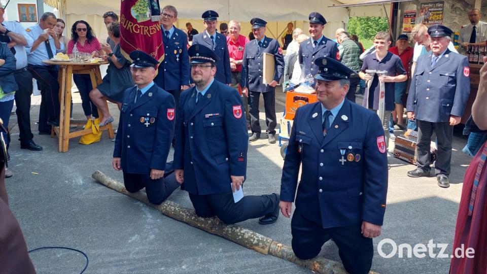Die Feuerwehr Burgtreswitz mit Vorsitzendem Christopher Hanauer (Mitte), zweitem Vorsitzenden Matthias Zeitler (links) sowie dem ehemaligen Kommandanten Peter Hartinger (rechts) auf dem Holzscheit kniend bitten die Feuerwehr Tradigist um die Übernahme der Ehrenpatenschaft für die Einweihung des neuen Feuerwehrhauses Burgtreswitz am 5. und 6. Juli 2024. Bild: gi
