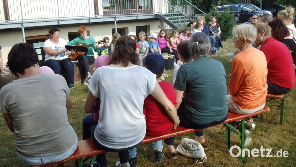 Kinder wie Erwachsene stimmten – von Lisamarie Schmidl mit der Gitarre begleitet – vor dem Entzünden des Johannisfeuers im Verlauf des Kleinkindergottesdienstes die Lieder „Lasst uns miteinander singen, loben, preisen den Herrn“ und „Gottes Liebe ist wunderbar“ an. Links mit Liederbuch: Gemeindereferentin Barbara Schlosser. Bild: u