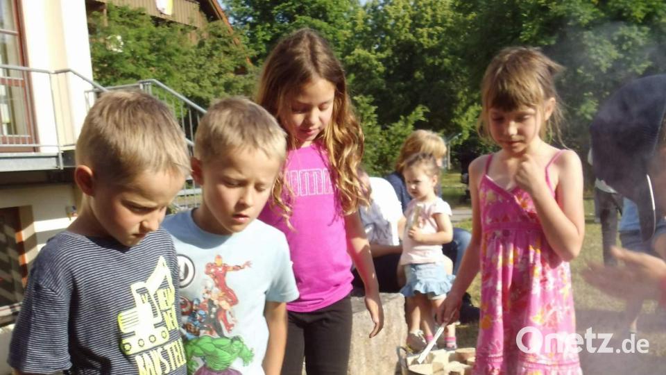 Die Jungen und Mädchen lassen große Vorsicht walten, als sie ihre Stäbchen und Holzscheite in das Johannisfeuer werfen, um es am Brennen zu halten. Bild: u