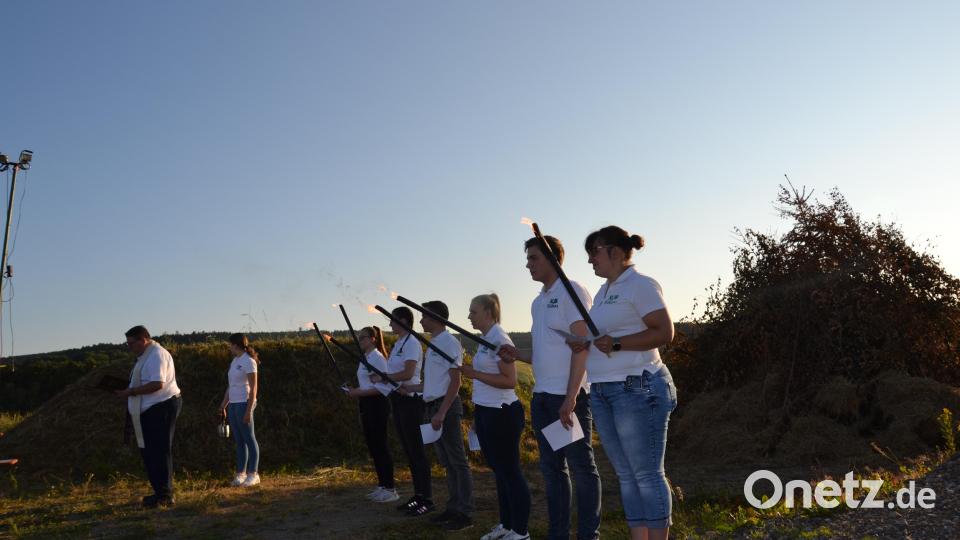 Mitglieder der Landjugend Tröbes stellen sich zur Segnung des Johannisfeuers auf und sprechen die Fürbitten. Bild: gi
