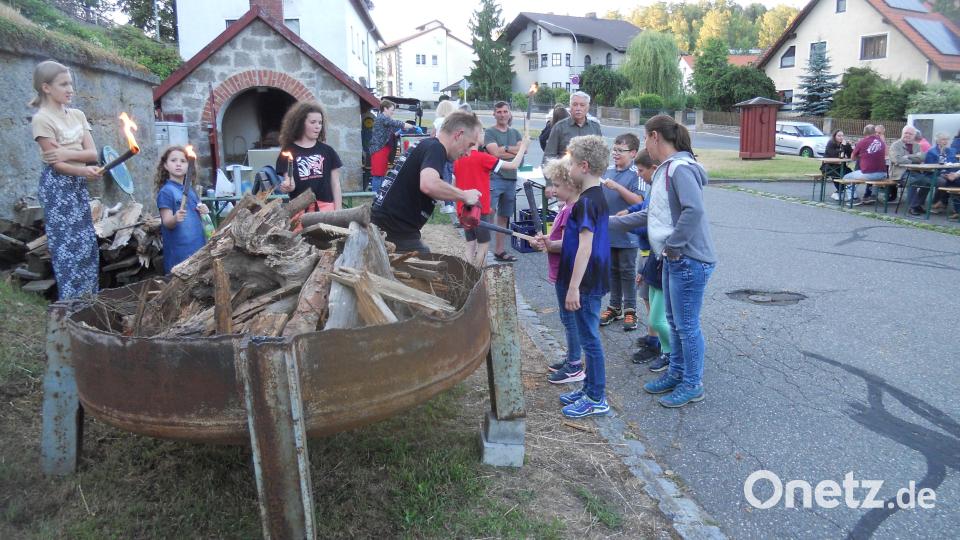 Kinder entzünden das Johannifeuer auf dem Ortsplatz in Flossenbürg. Bild: jba