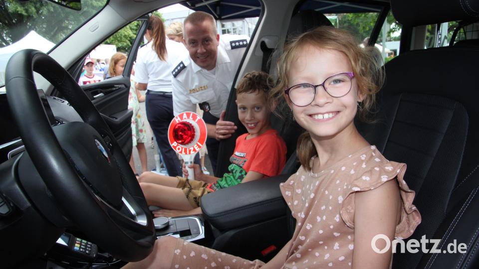 Die beiden achtjährigen Lena und Moritz aus Schönkirch durften in einem Polizeiauto Platz nehmen. Polizeihauptkommissar Andreas Sennert freut sich über das Interesse. Bild: kro